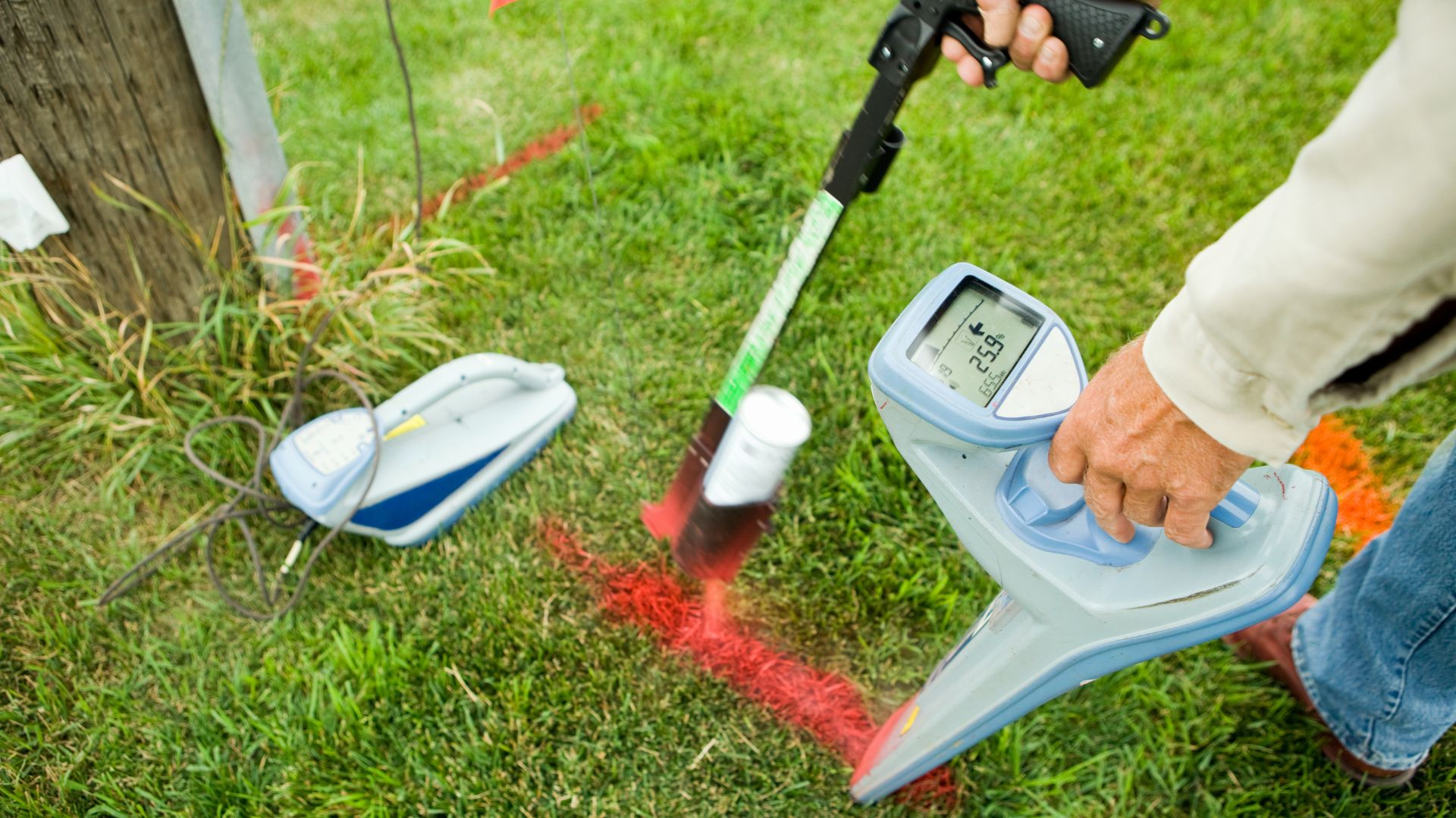 A man is using a garden thermometer in the grass